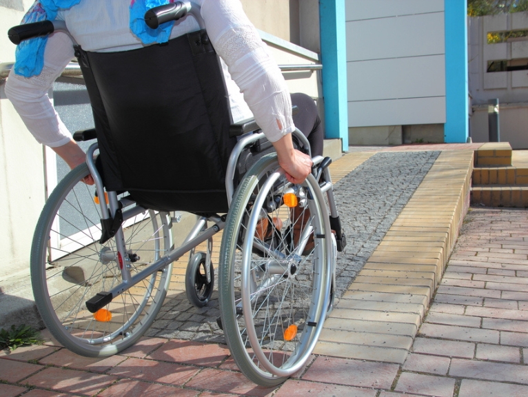 A person in a wheelchair uses a ramp to gain access to a dental practice