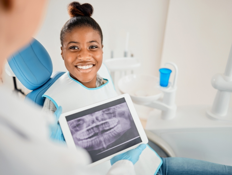 a dentist explains to a young patient using a tablet