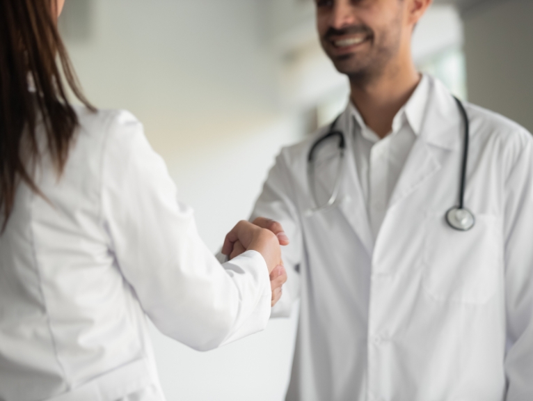 A satisfied patient shakes hands with a dentist